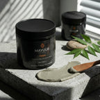 Mayuur Detox mask jar with a spoonful of mask on a stone surface with leaves.