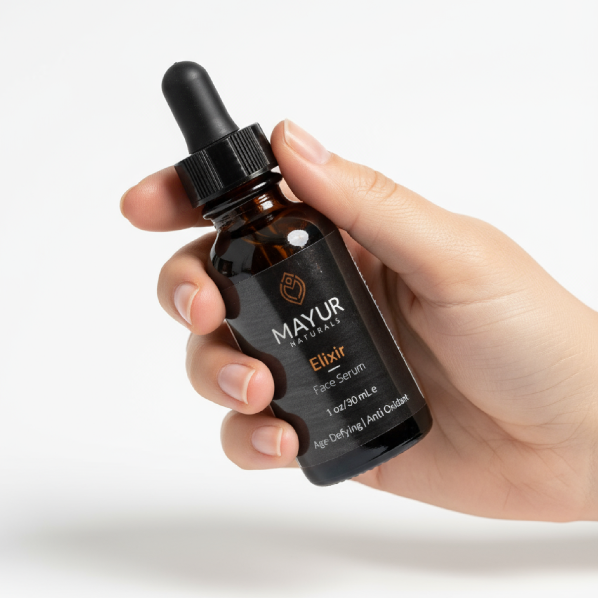 Hand holding a Mayur Elixir bottle against a white background