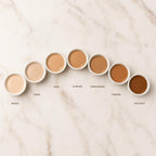 Row of cosmetic containers with color names on a marble surface