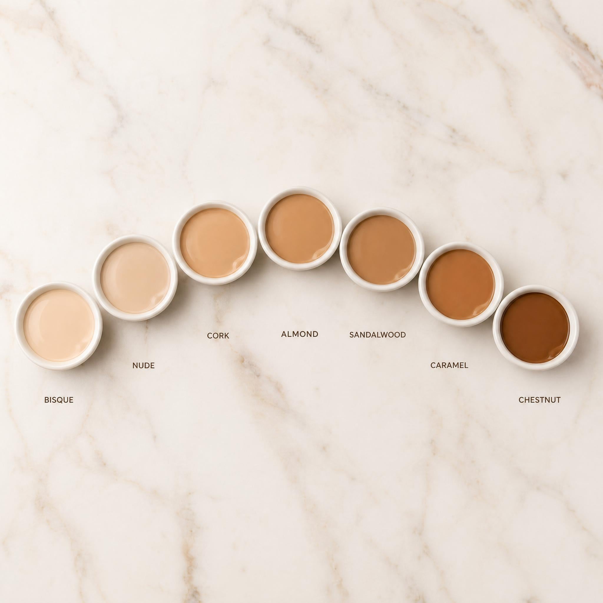 Row of cosmetic containers with color names on a marble surface