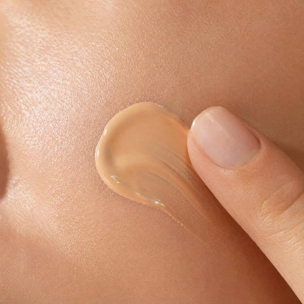Close-up of a hand applying beige cream to skin