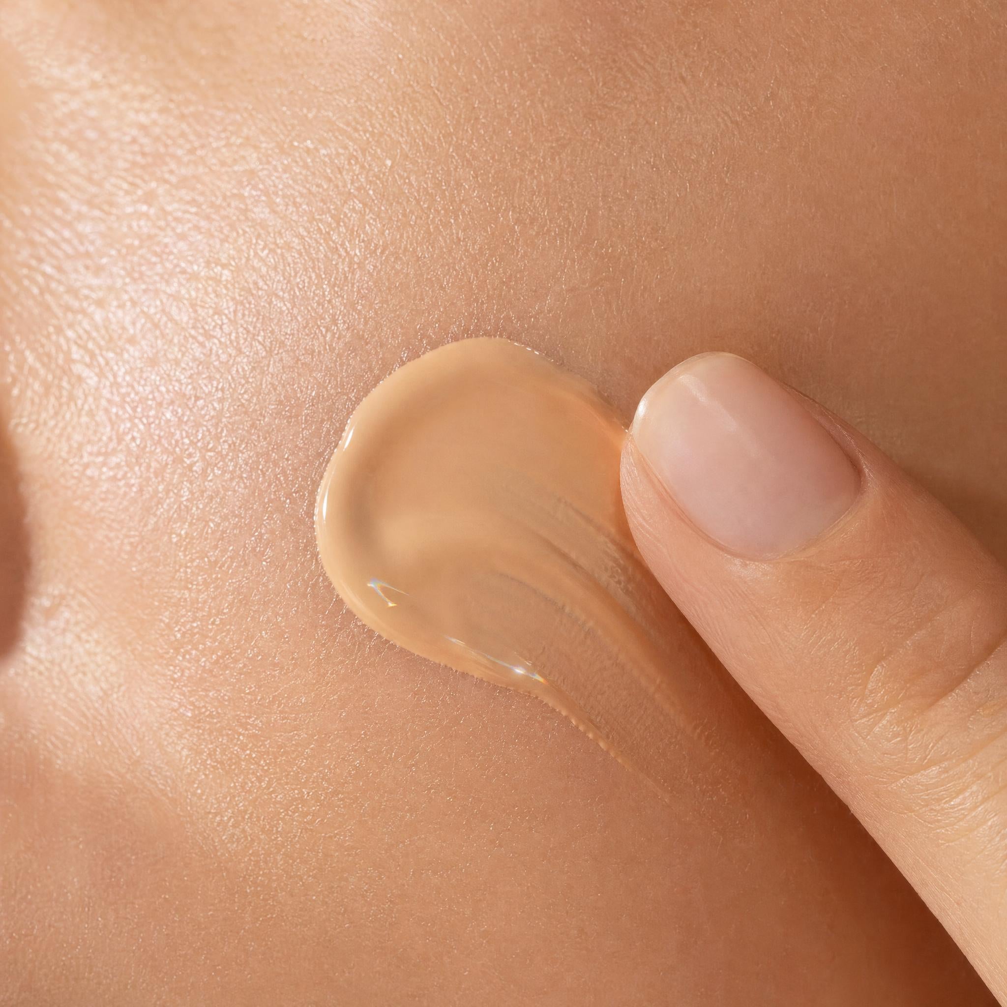 Close-up of a hand applying beige cream to skin