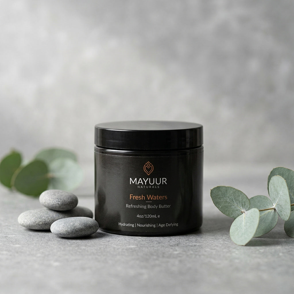 Black jar of Mayuur Fresh Waters body butter on a gray surface with eucalyptus leaves.