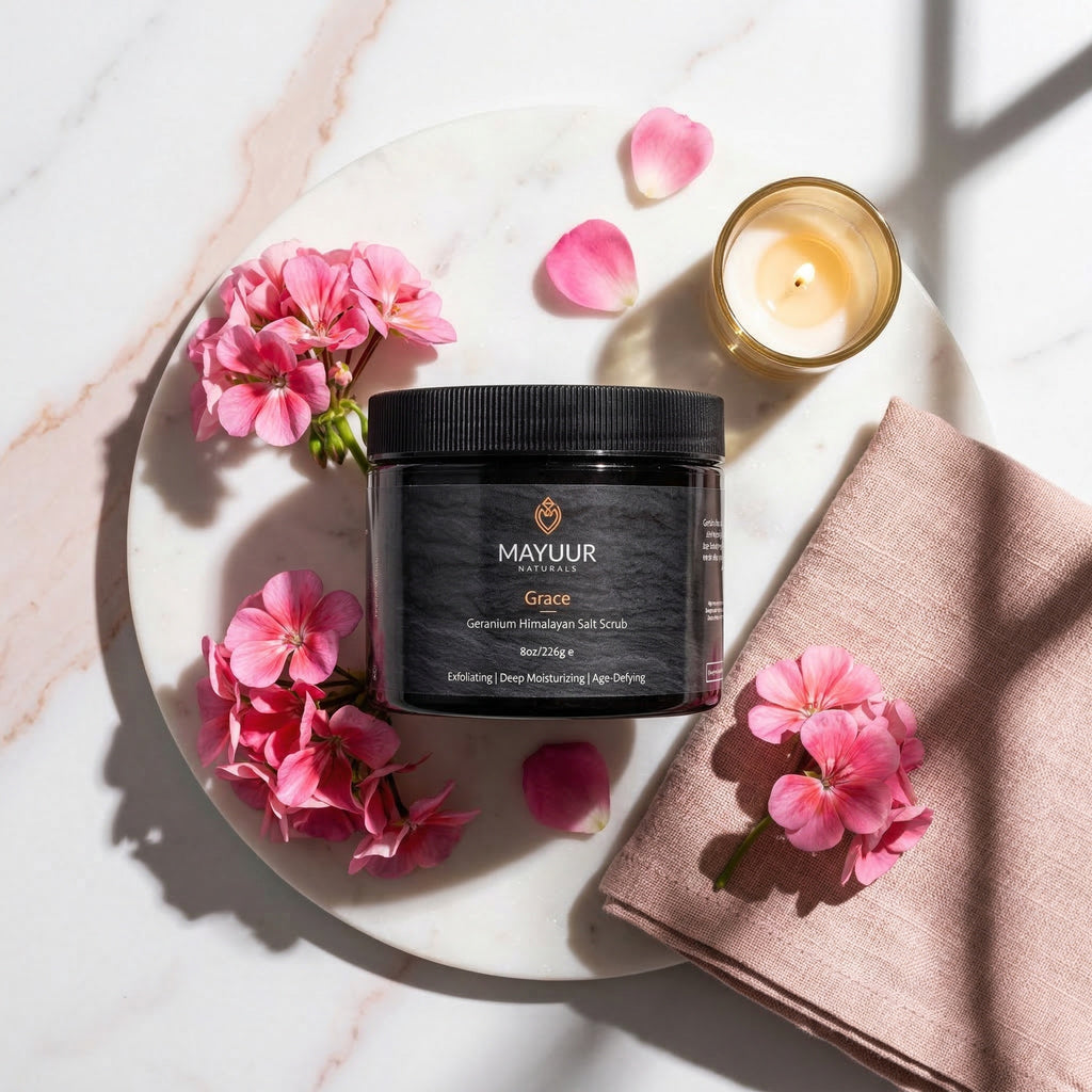 Mayuur Grace salt scrub with pink flowers and a candle on a marble surface