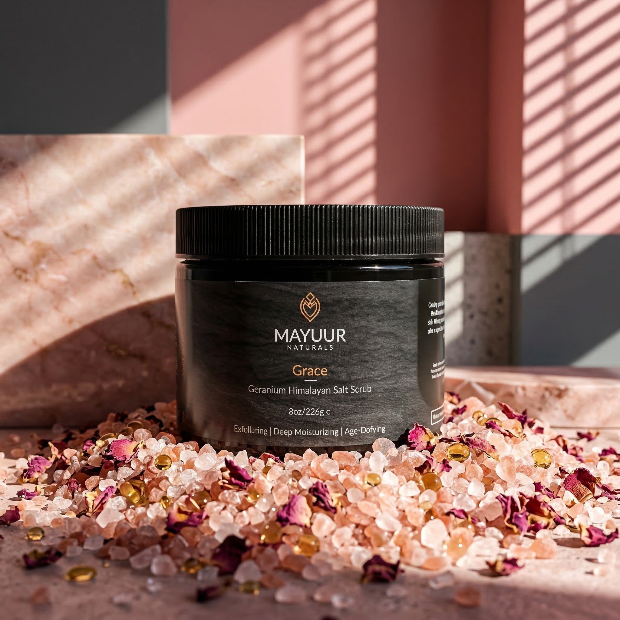 Mayuur Naturals Grace Geranium Himalayan Salt Scrub jar with salt and flowers on a textured surface.