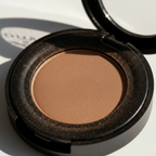 Compact brown powder in an open case on a white background