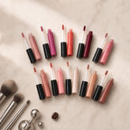 Collection of lip glosses and applicators on a beige surface