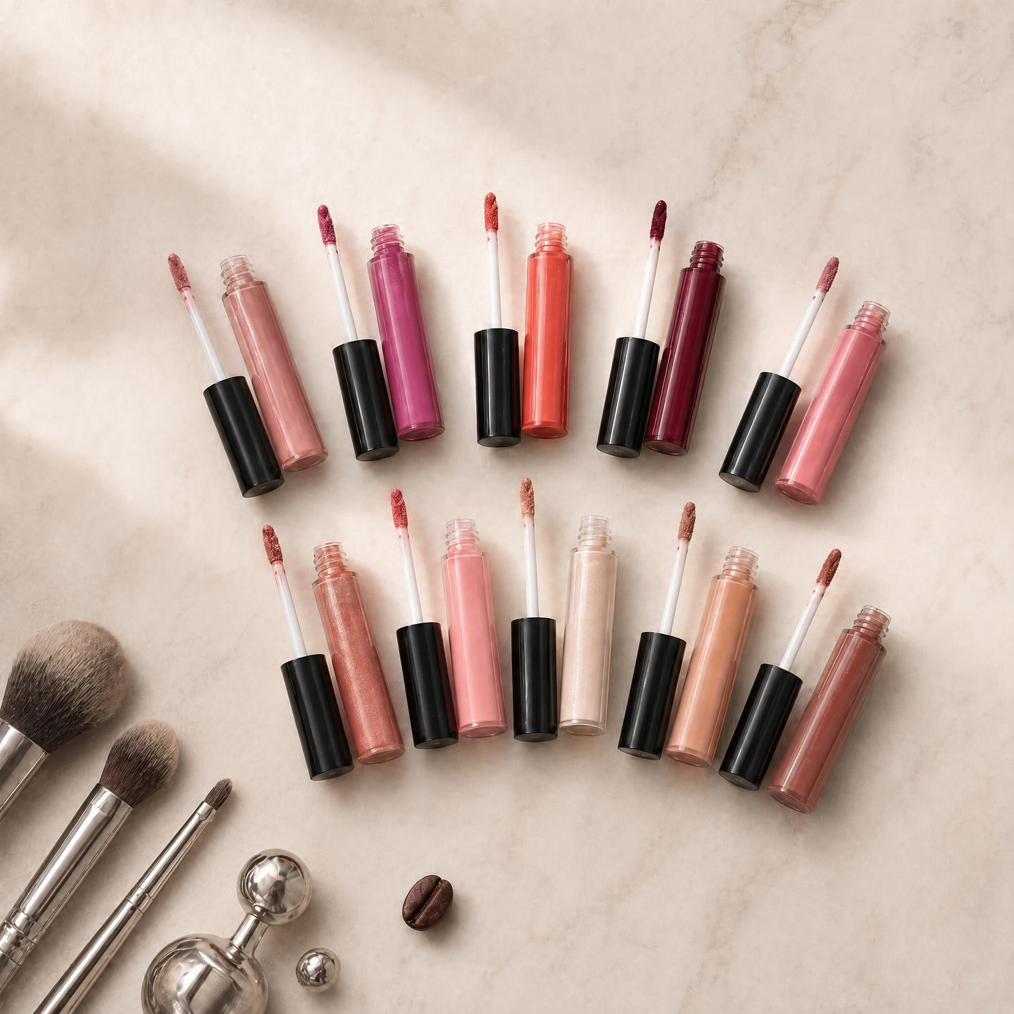 Collection of lip glosses and applicators on a beige surface